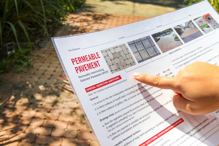 A person points at a permeable pavement checklist.
