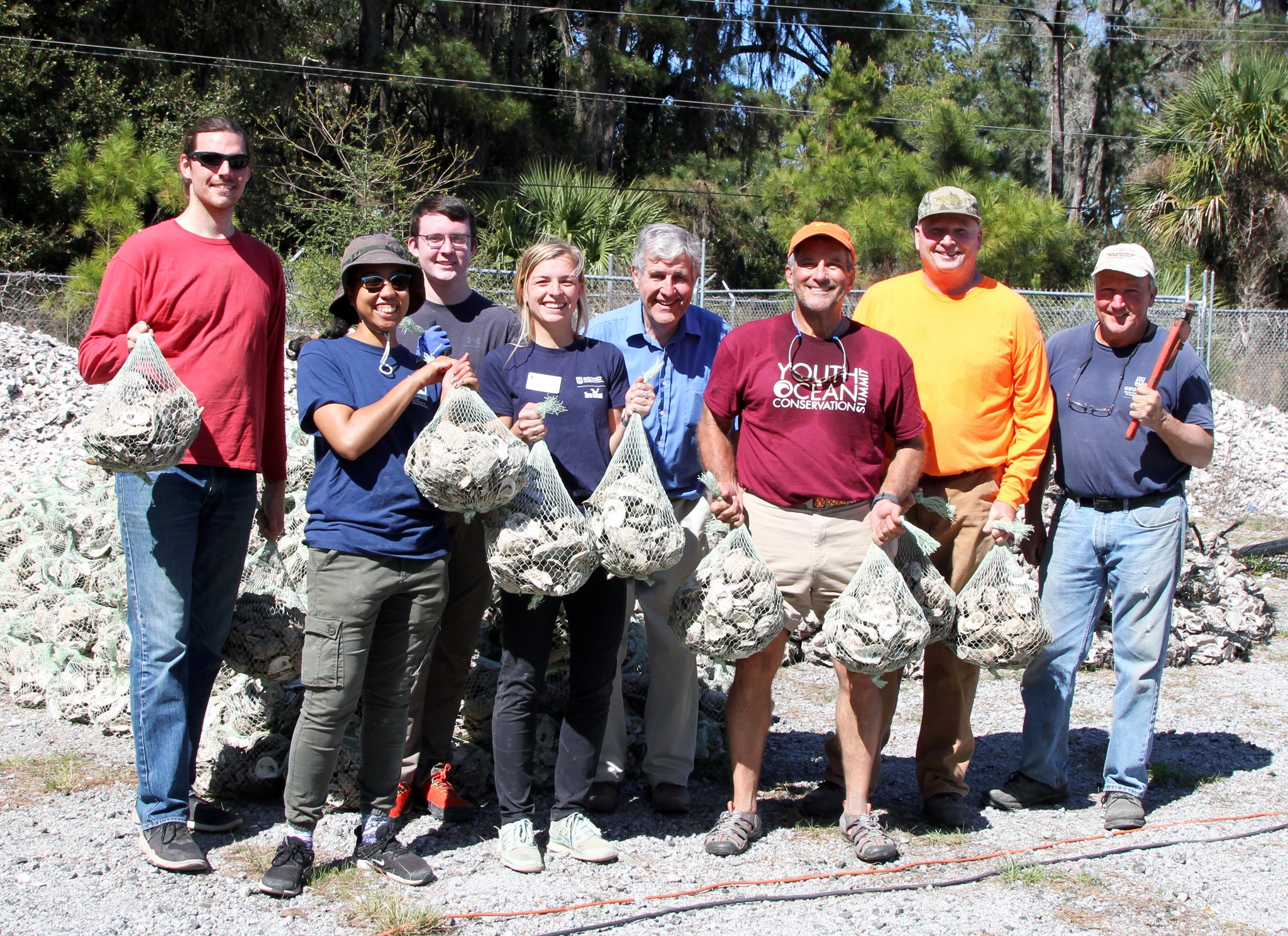 A group poses with bagged oyster shells