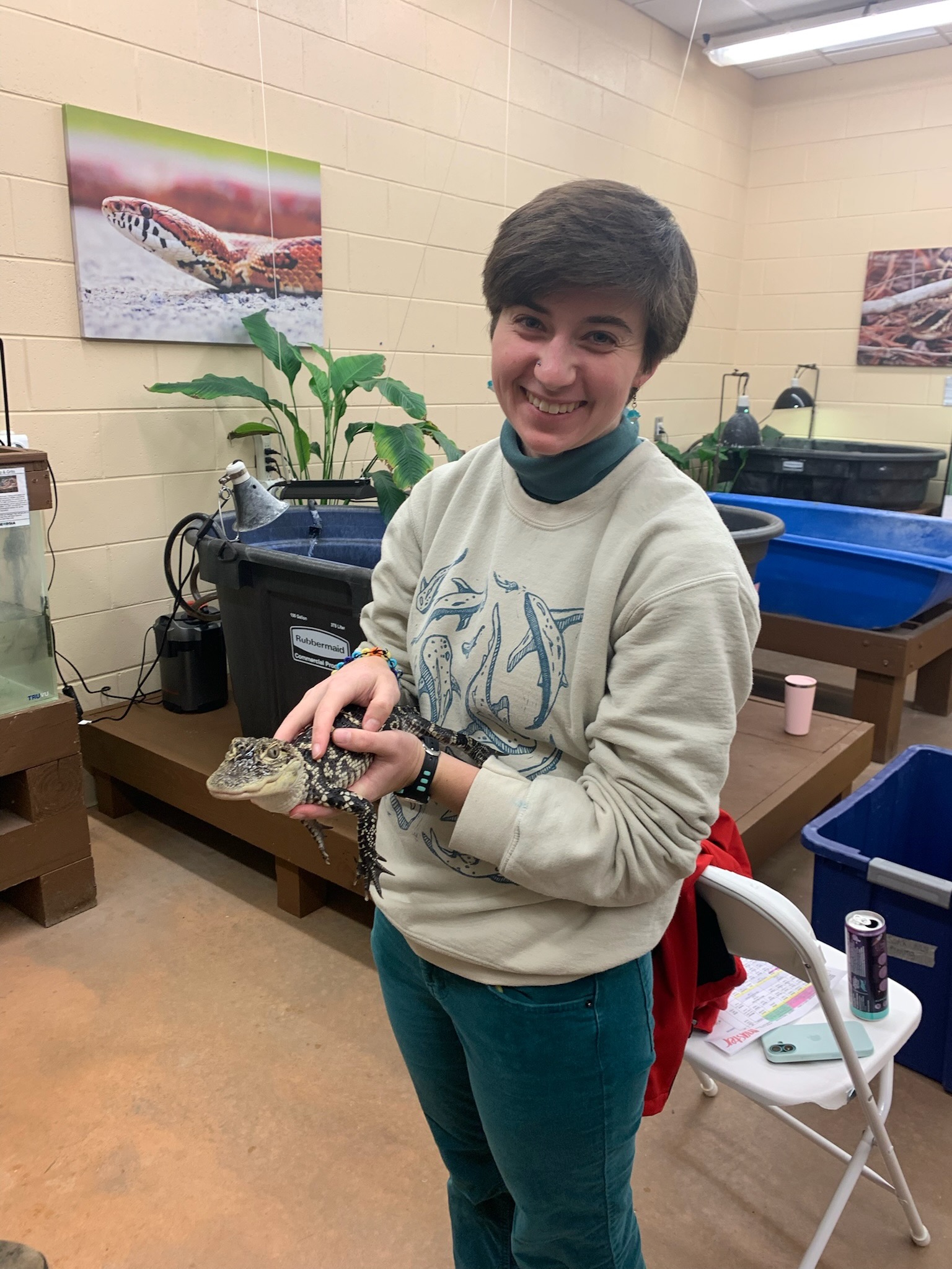 a young adults smiles while holding a small alligator