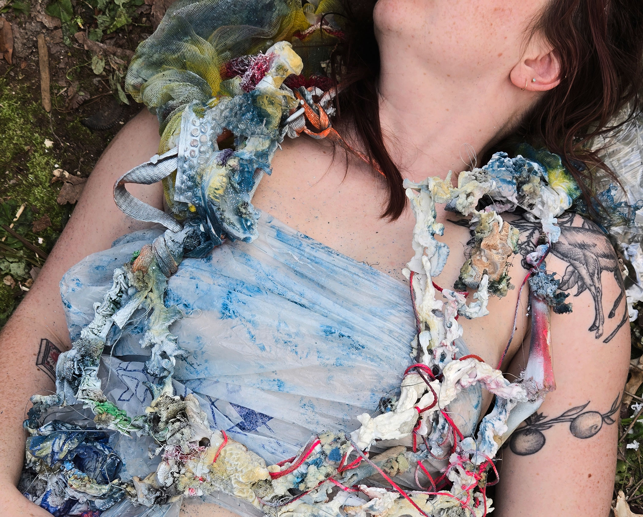 an abstract art piece made from reclaimed materials is draped on a model