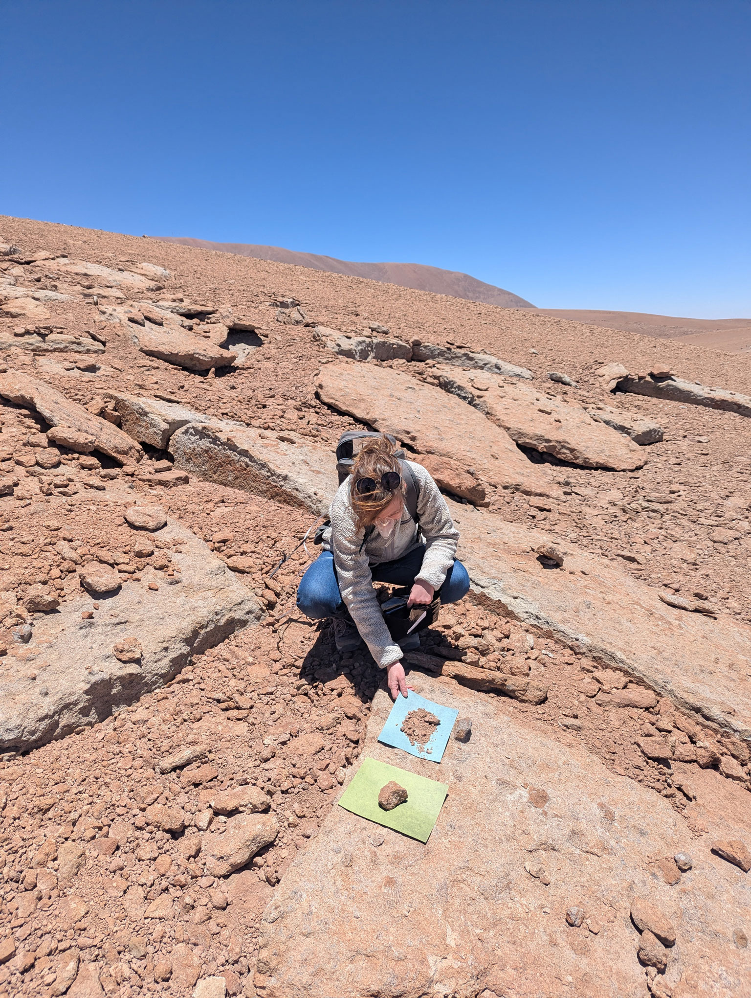 a woman kneels down in a desert environment