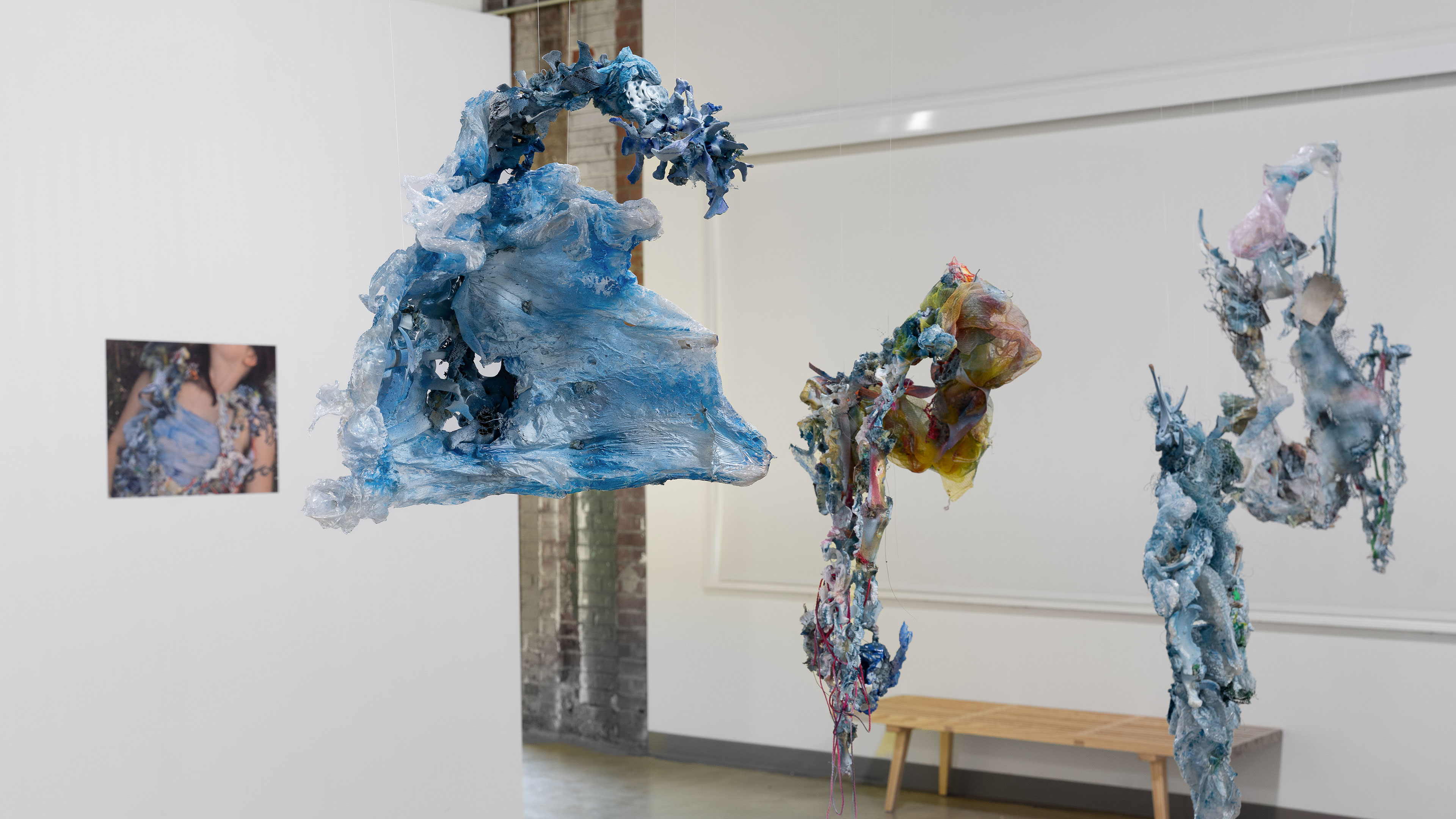 abstract blue shapes hang from a ceiling in an art exhibit