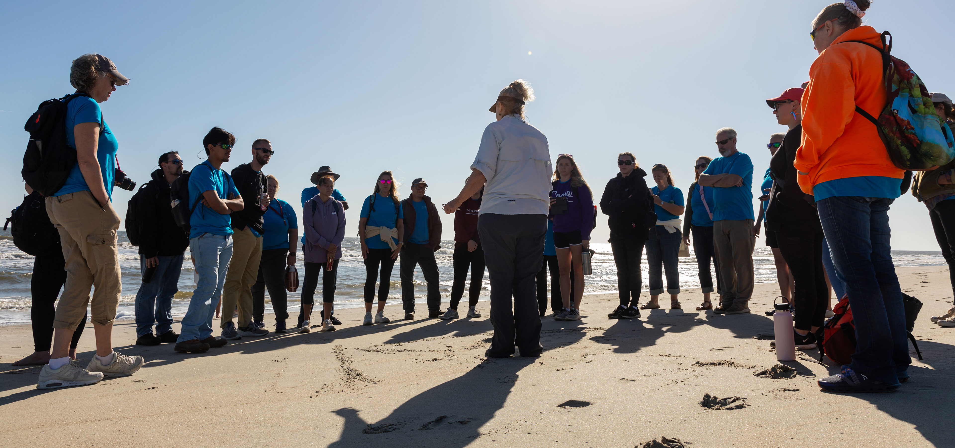 group of adults standing in discussion on a beach
